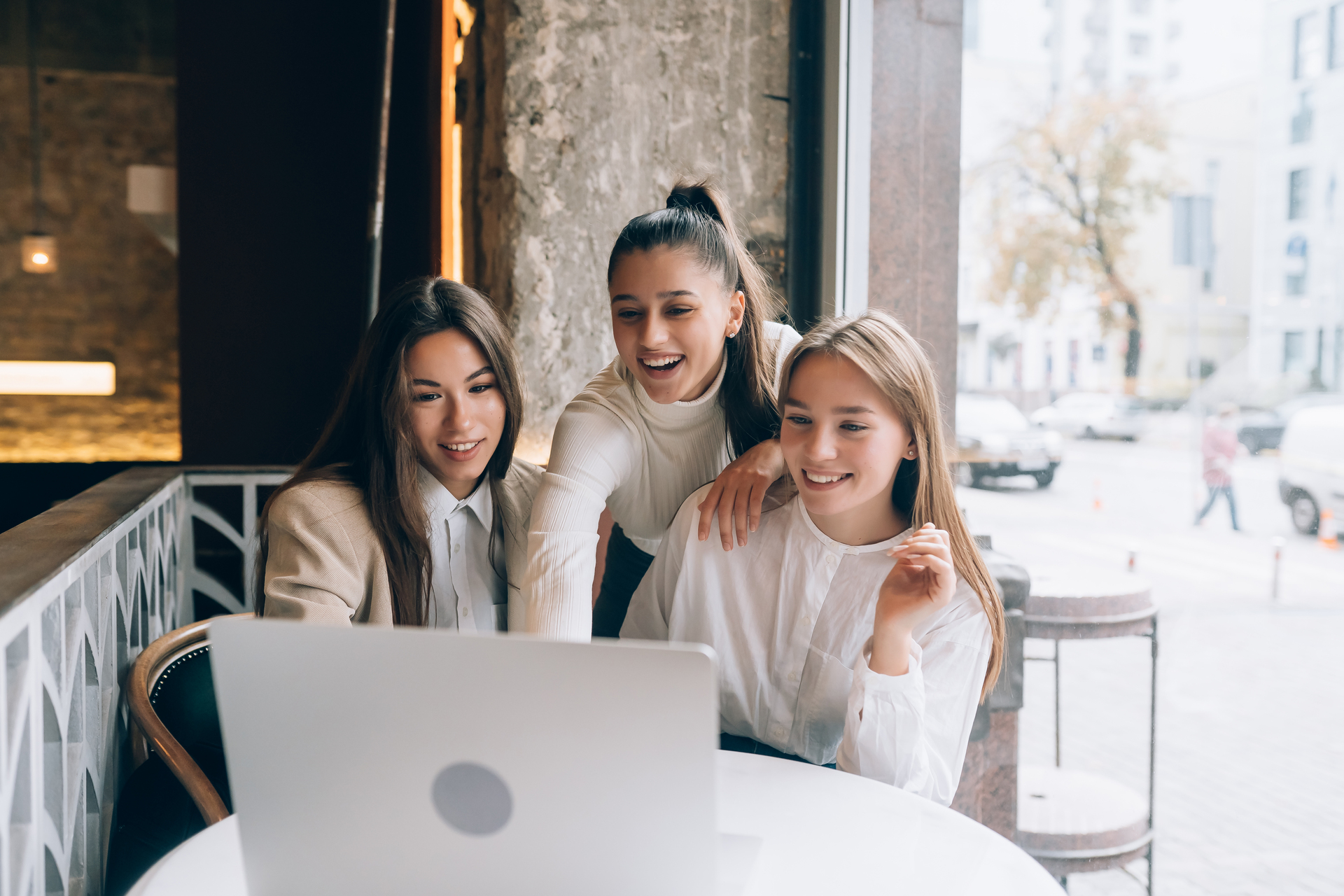 A group of gen z women in a cafe are looking at a laptop
